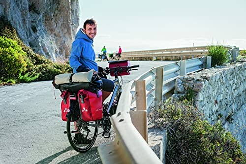 Fietser op bergweg met rode fietstassen