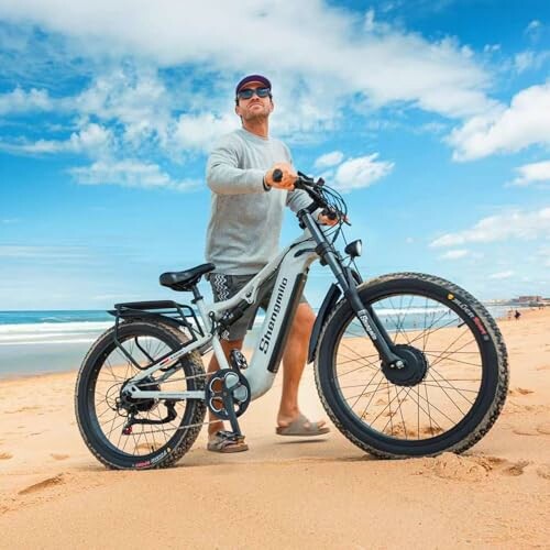 Man met elektrische fiets op het strand