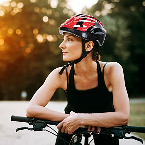 Vrouw met rode fietshelm rust op fiets.